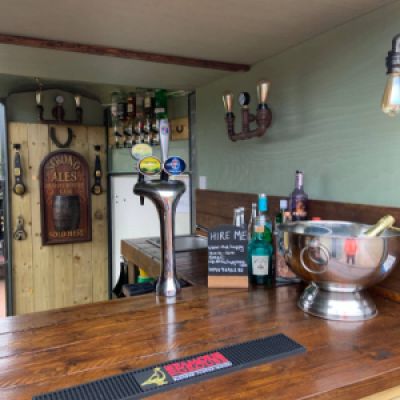 A view inside The Hoppy Mare mobile pub with beer pumps, drinks selection and signs