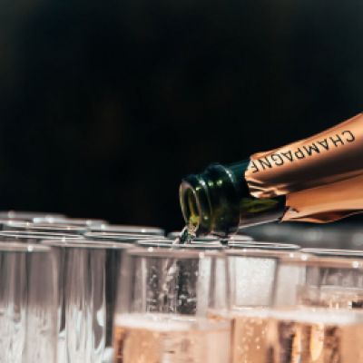 Serving champagne for a function Pouring sparkling wine into flute glasses
